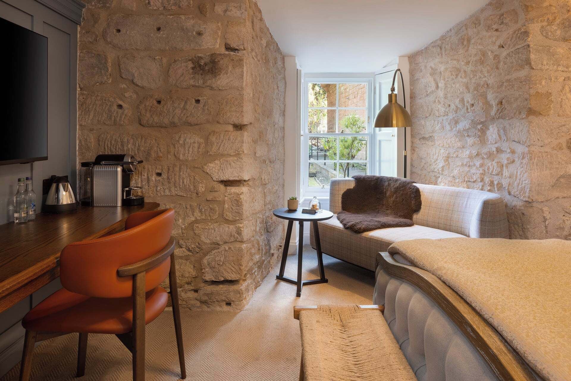 A cozy room with a stone wall, a sofa, a chair, a small table, and a television.