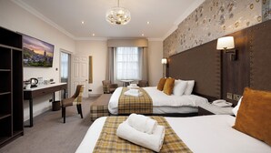 Une chambre d’hôtel avec deux lits, un bureau, une chaise, une table et une grande fenêtre.