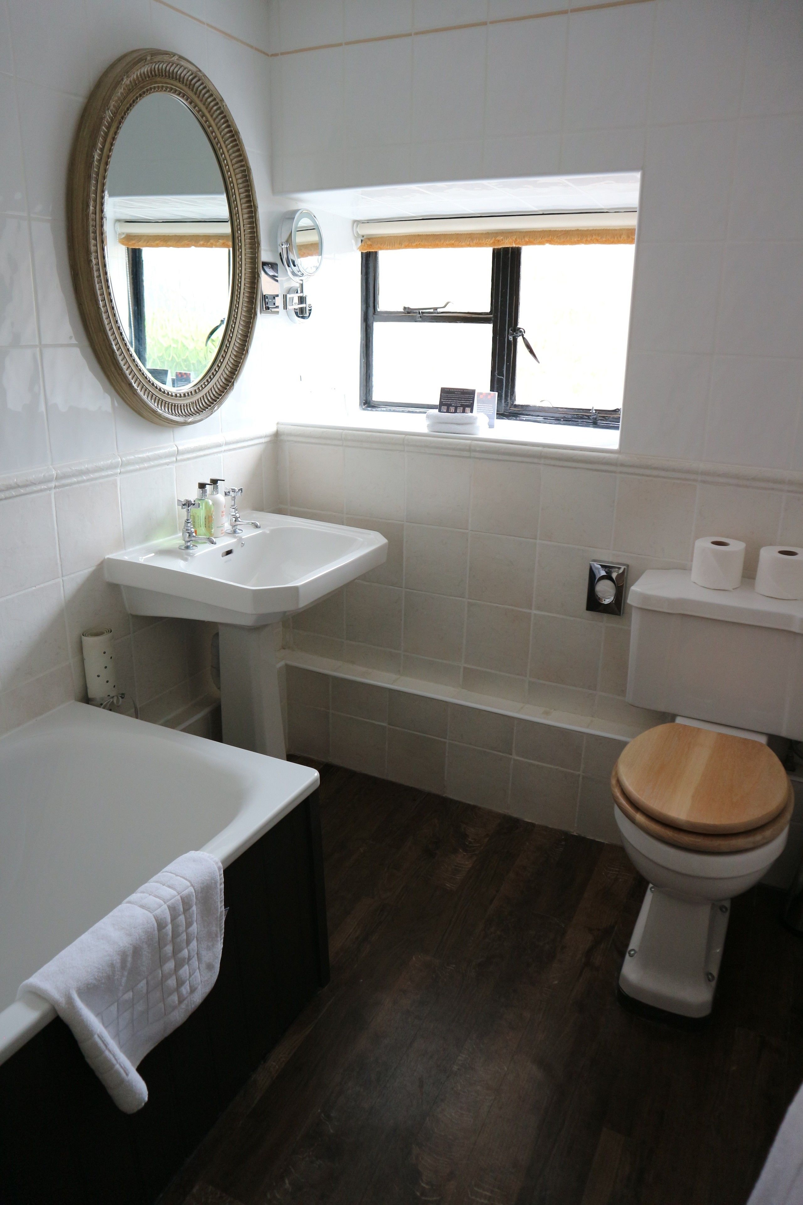 A bathroom with a white sink, a wooden toilet, a bathtub, and a mirror.