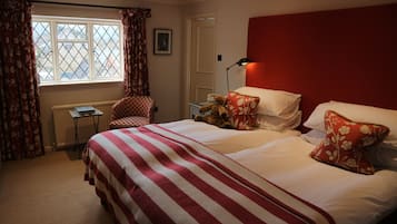 A hotel room with a large bed, a chair, a desk, and a window with curtains.