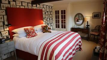 Une chambre bien rangée, avec un grand lit, une commode, une chaise et un miroir.