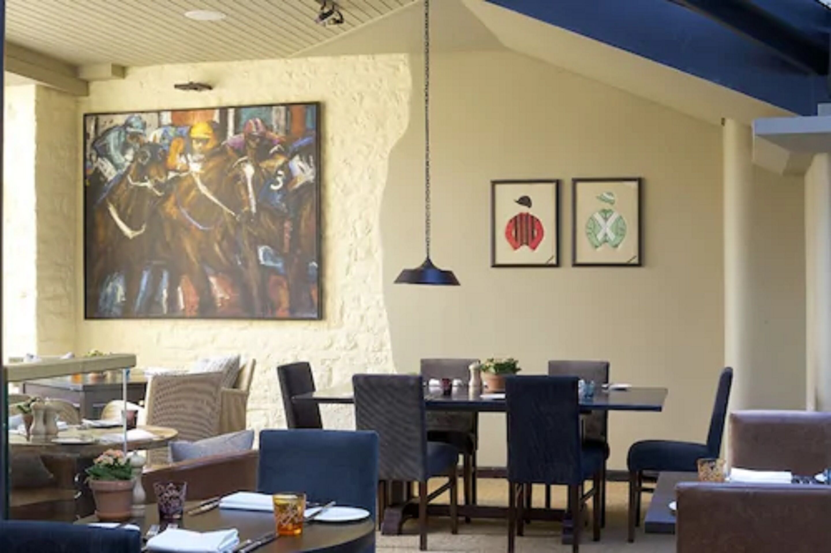 Un comedor con un cuadro abstracto grande, dos obras de arte enmarcadas y una lámpara colgante.
