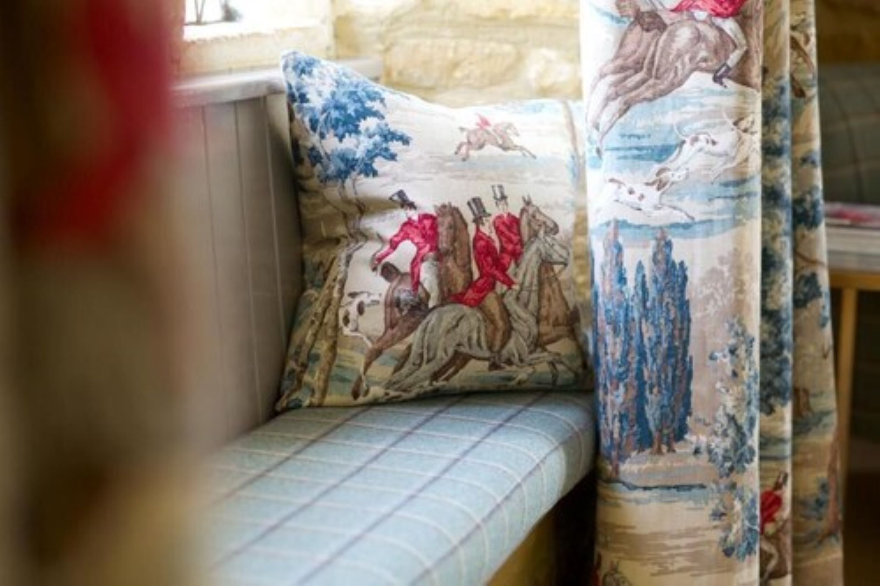 Un sofá con un cojín estampado y una cortina con diseño de paisaje.