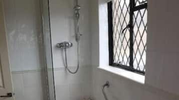 Un baño con bañera, ducha y ventana con reja de metal.