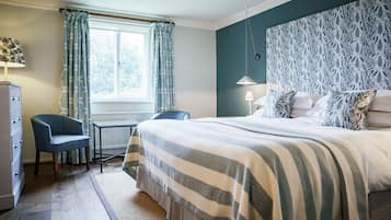 A bedroom with a bed, a chair, a desk, and a window with curtains.
