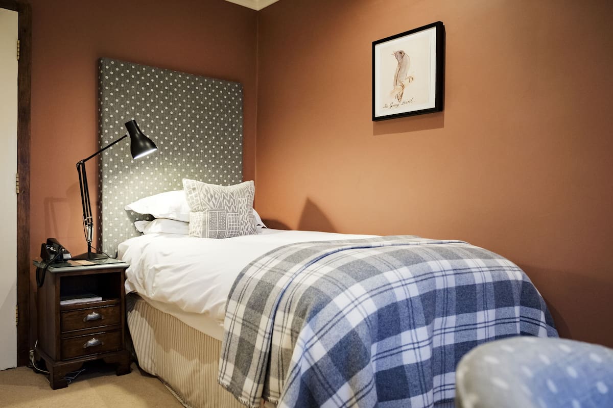 A bedroom with a bed, a nightstand, a lamp, a framed picture on the wall, and a polka dot headboard.