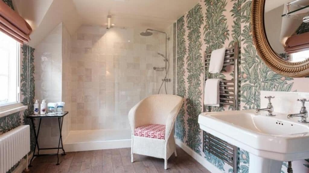 Ein Badezimmer mit Dusche, Waschbecken, Stuhl und Spiegel.