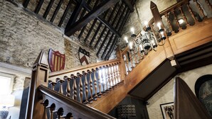 A wooden staircase with a balustrade, a chandelier, and a shield-shaped wall decoration. - Bay Tree Hotel (Burford)