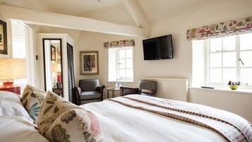 A hotel room with a large bed, a TV mounted on the wall, a small table with a lamp, and a window with a view of the outside.
