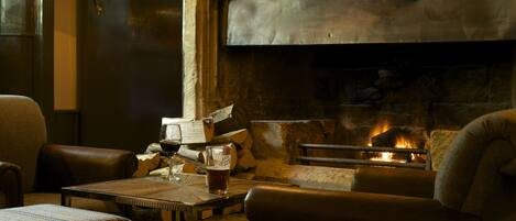 A cozy room with a fireplace, leather furniture, and a table with a glass of beer.