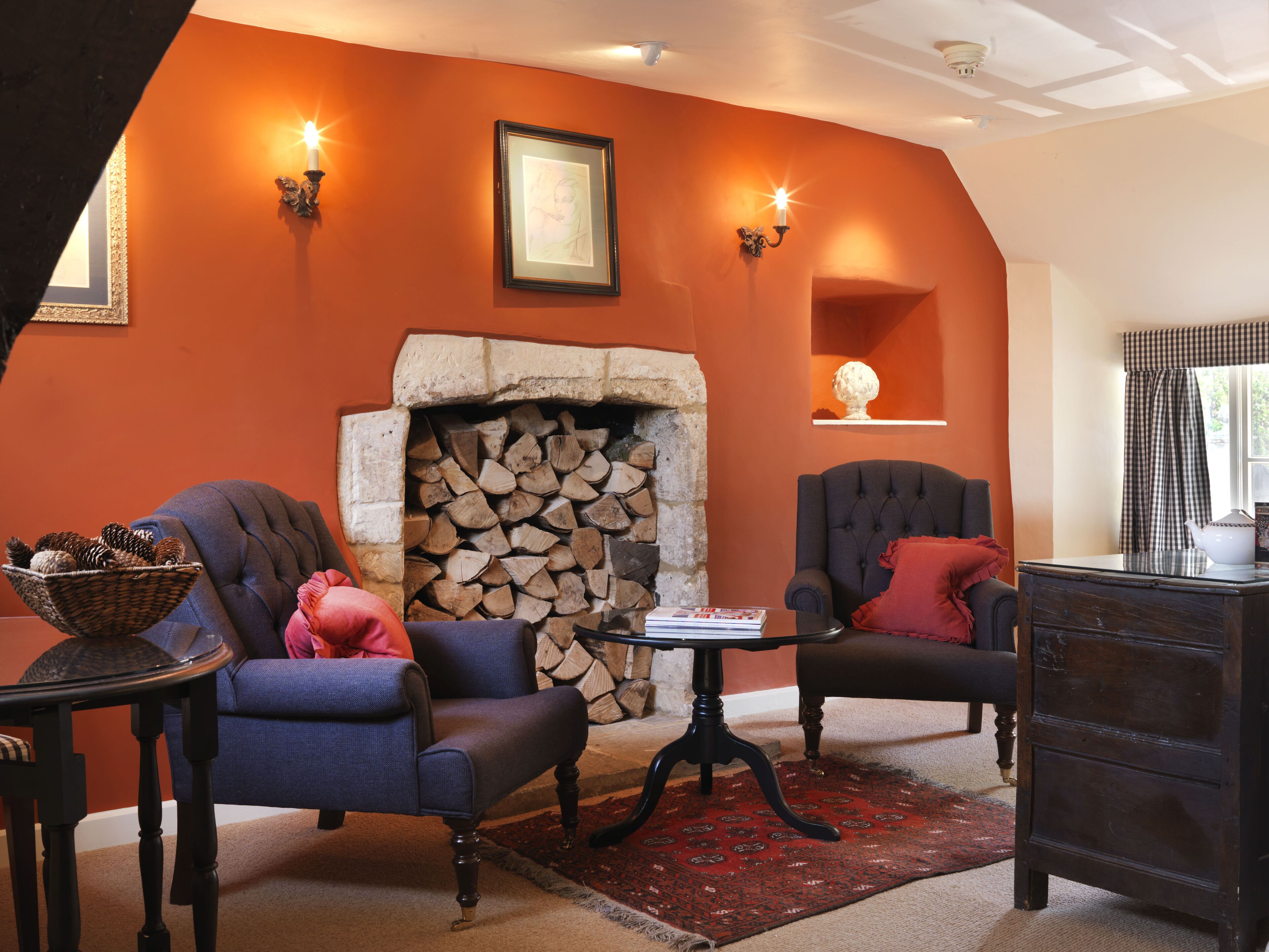 A cozy living room with a stone fireplace, two armchairs, a small table, and a decorative bowl on a side table.