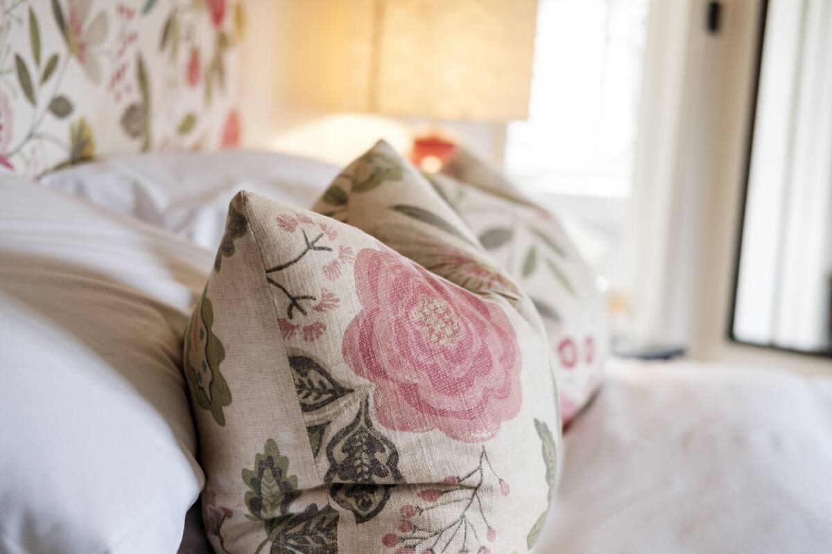 Uma cama com almofadas estampadas e uma luminária ao fundo.
