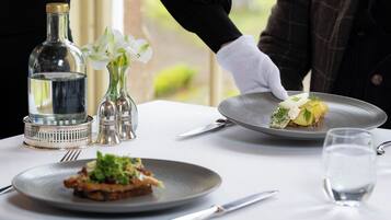 Una mesa con platos de comida, una botella y un jarrón con flores.