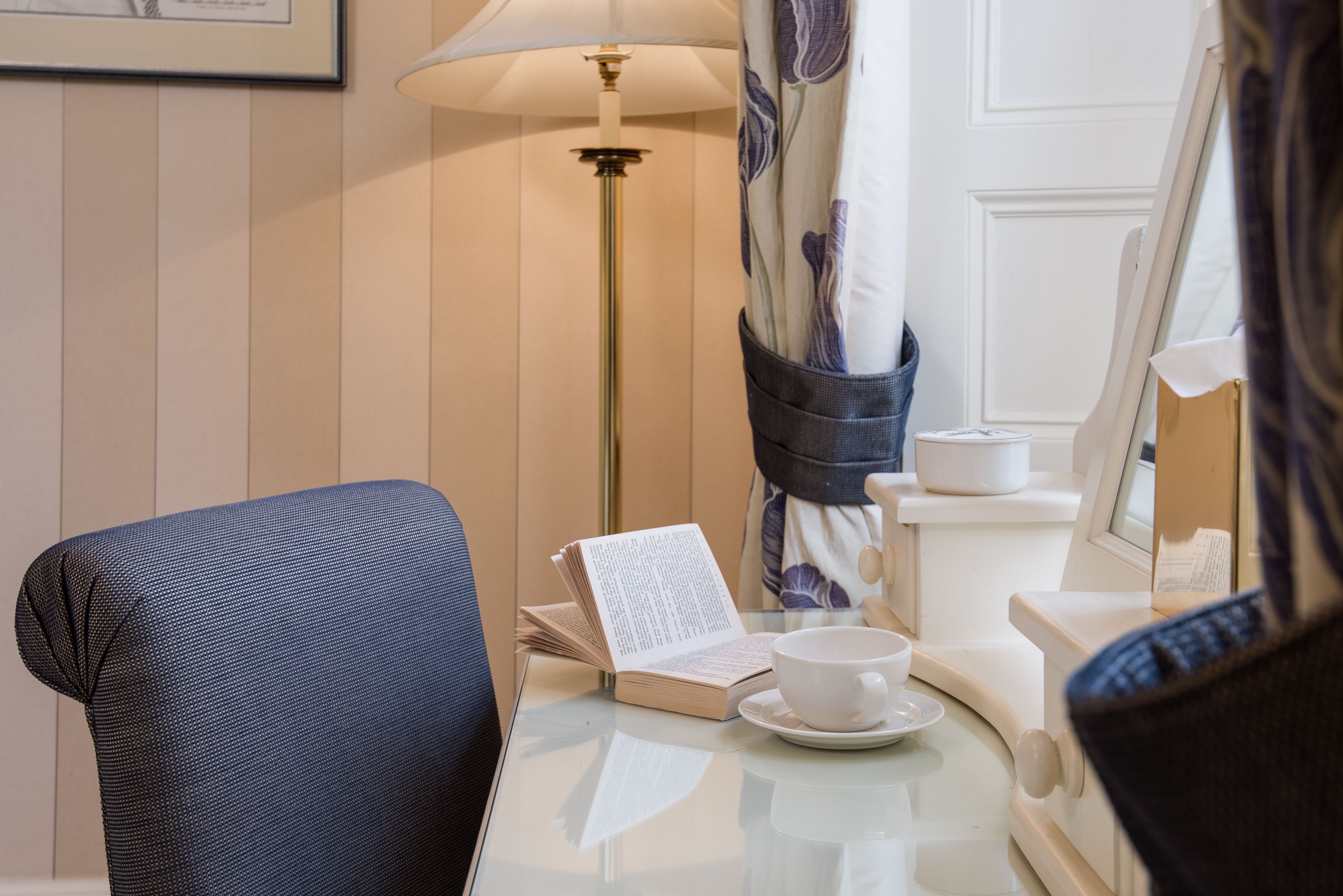 Une chambre d’hôtel avec un lit, une table de chevet avec une lampe, un livre et une tasse.