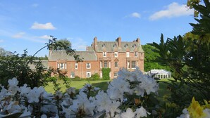 A large brick building with multiple windows and a lawn in front. - Cringletie House Hotel (Peebles)