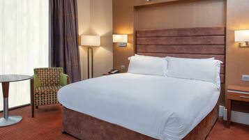 Una habitación de hotel con una cama grande, una silla, una mesa y una lámpara.