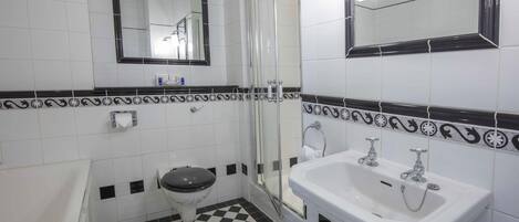 Un baño con piso a cuadros, un inodoro, un lavamanos y una ducha.