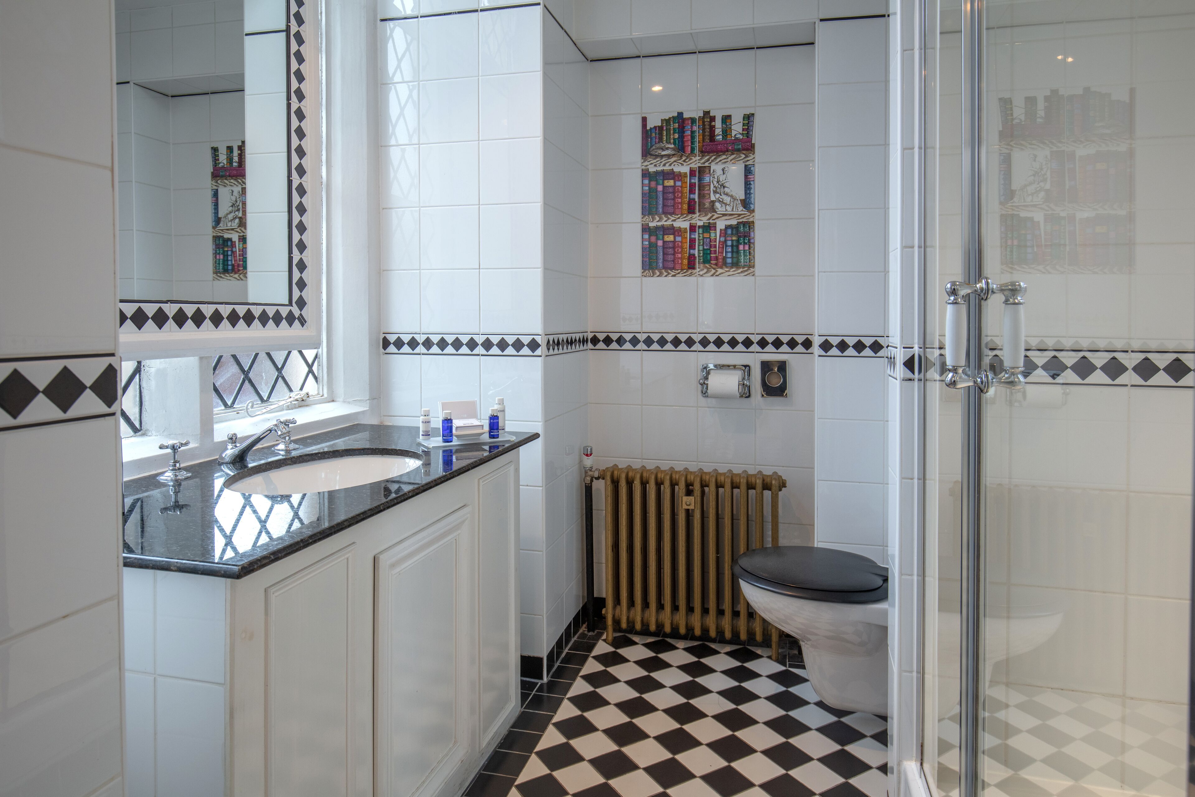 A bathroom with a checkered floor, a toilet, a sink, a mirror, and a shower.