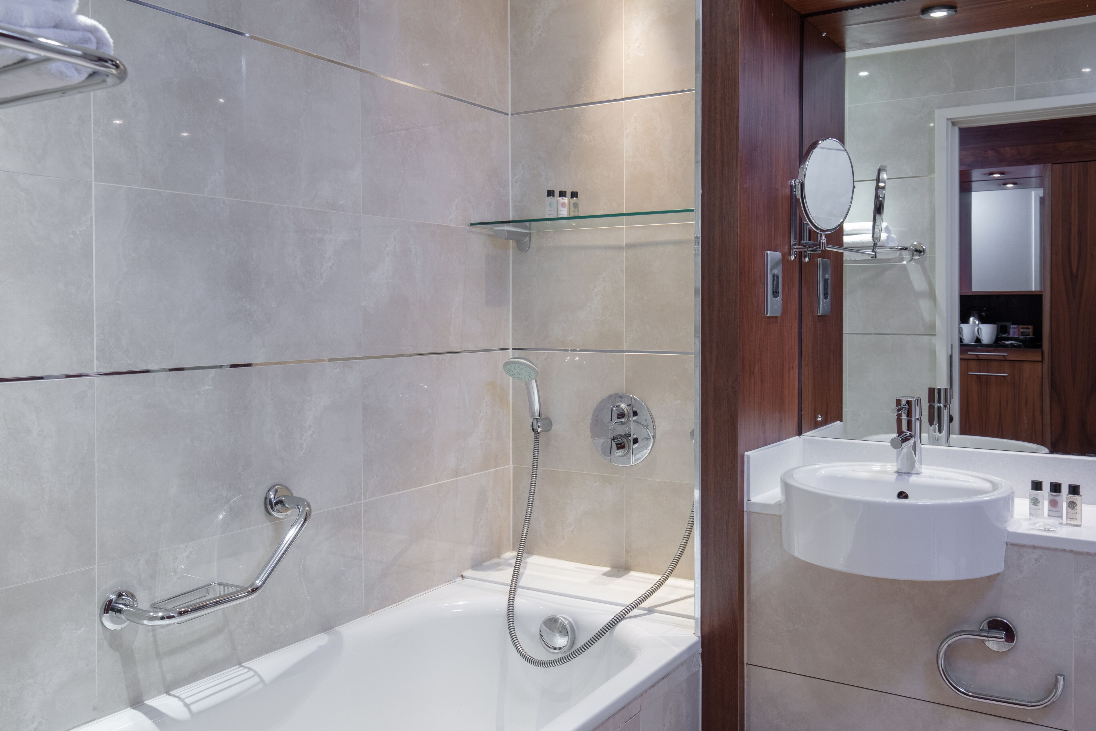 Een moderne badkamer met een bad, douche en wastafel.