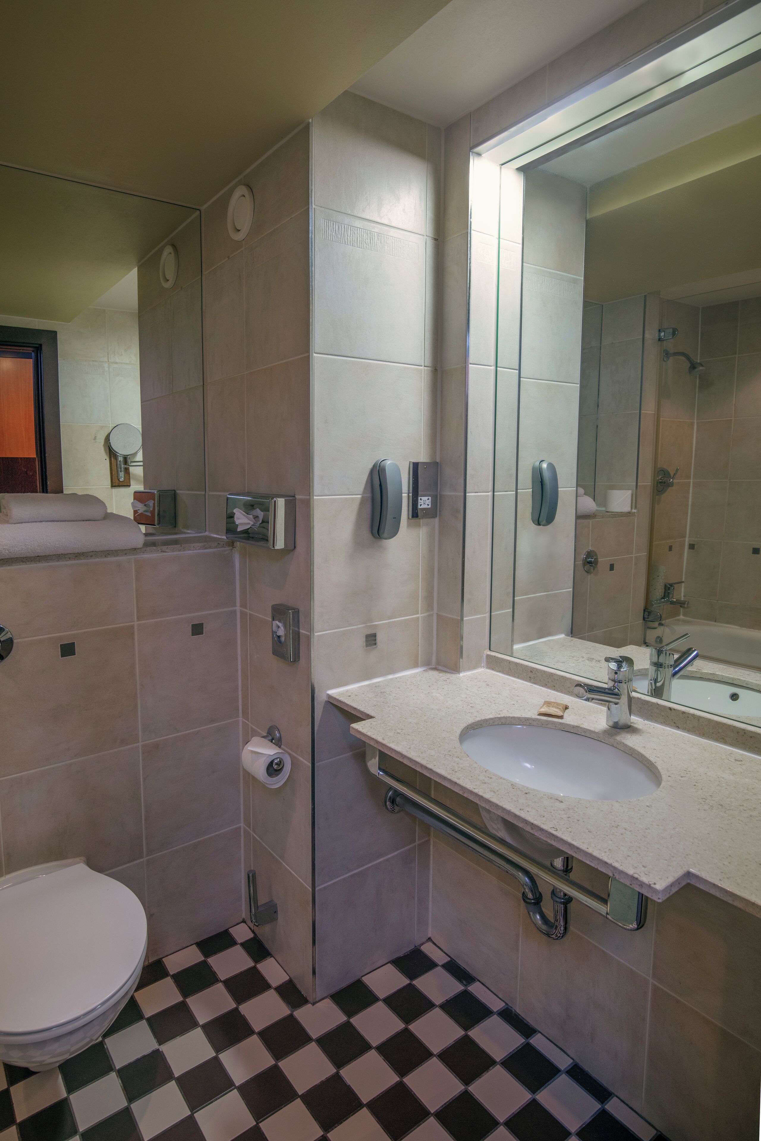 Un baño con lavamanos blanco, inodoro, espejo y zona de ducha.
