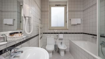 A modern bathroom with a sink, toilet, bidet, and bathtub.