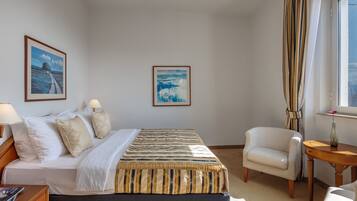 Ein Hotelzimmer mit einem Bett, zwei Stühlen, einem kleinen Tisch und zwei gerahmten Bildern an der Wand.