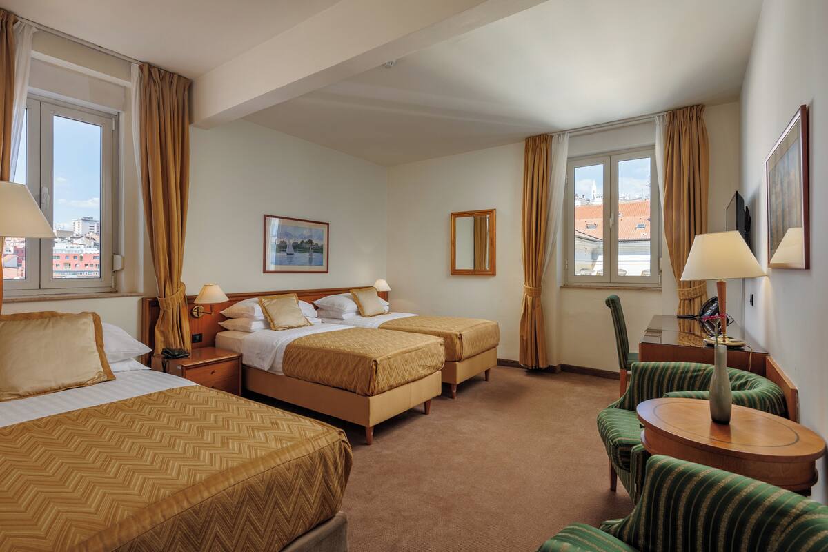 Habitación de hotel con dos camas, un sofá, una mesa y un televisor.