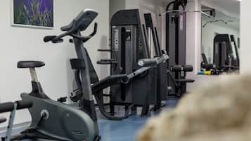Un gimnasio con equipo de ejercicio, incluyendo una bicicleta estática, una cinta de correr y máquinas de pesas.