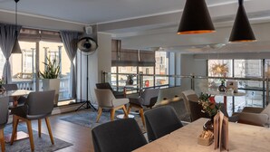 A modern dining area with a marble table, grey upholstered chairs, and pendant lighting.