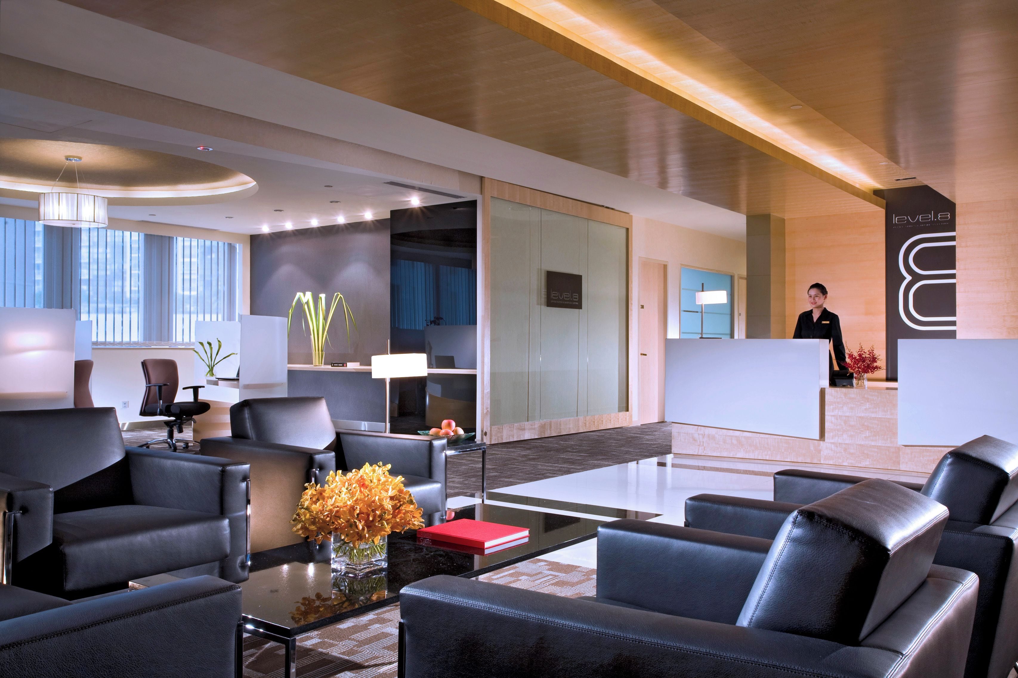 A modern hotel lobby with leather seating, a reception desk, and a large window.