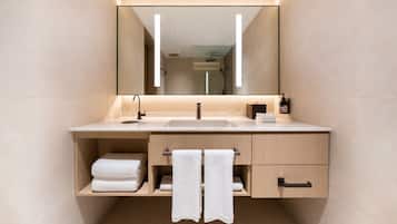 Un baño moderno con un espejo grande, un lavamanos, un perchero para toallas y un armario.