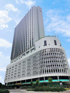 Ein Hotel mit einem hohen, zentralen Turm, einem gewölbten Unterteil und einem Schild, das darauf hinweist, dass es sich in Singapur befindet.