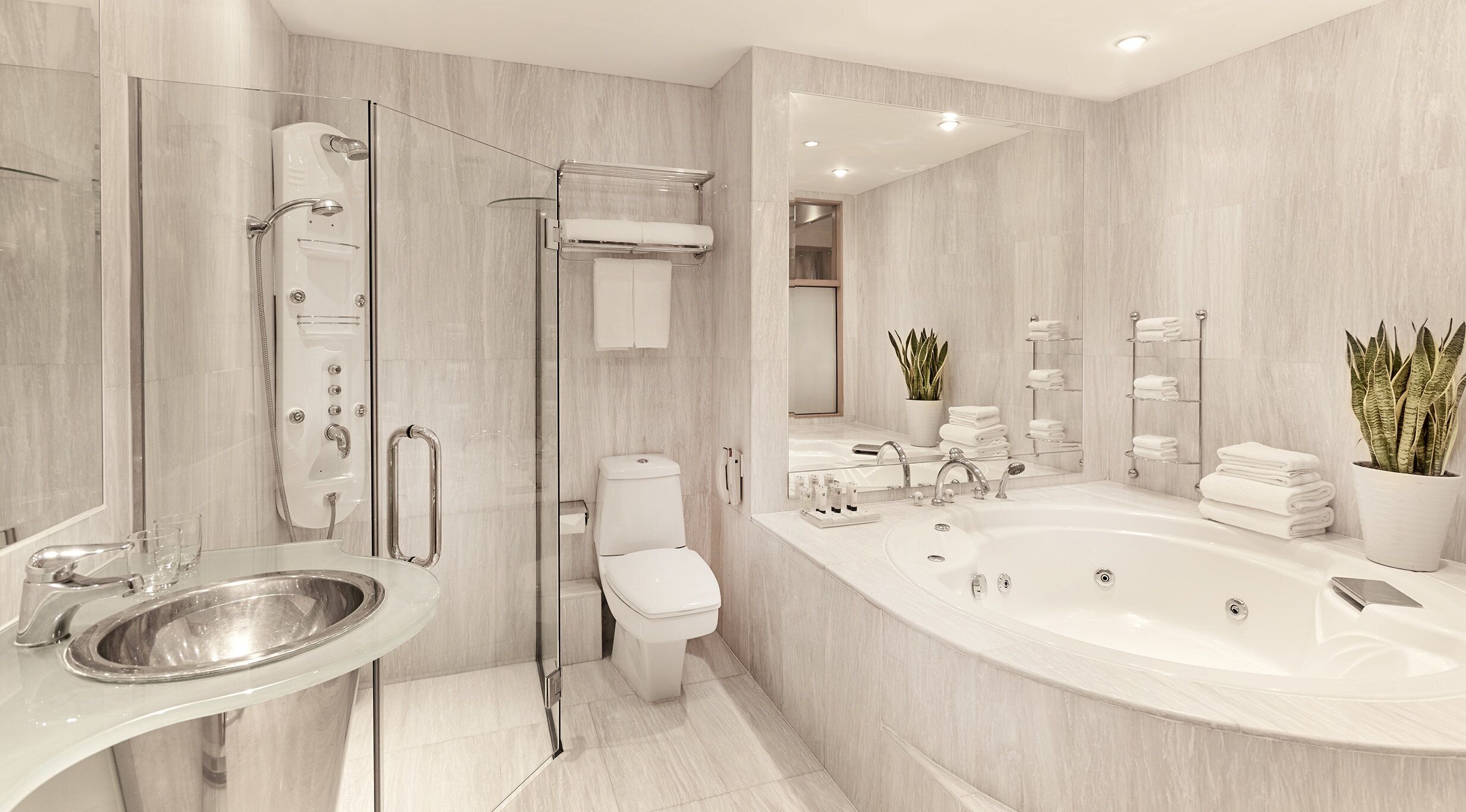 A modern bathroom with a glass shower enclosure, a standalone sink, a toilet, a large freestanding bathtub, and a mirror above the sink.