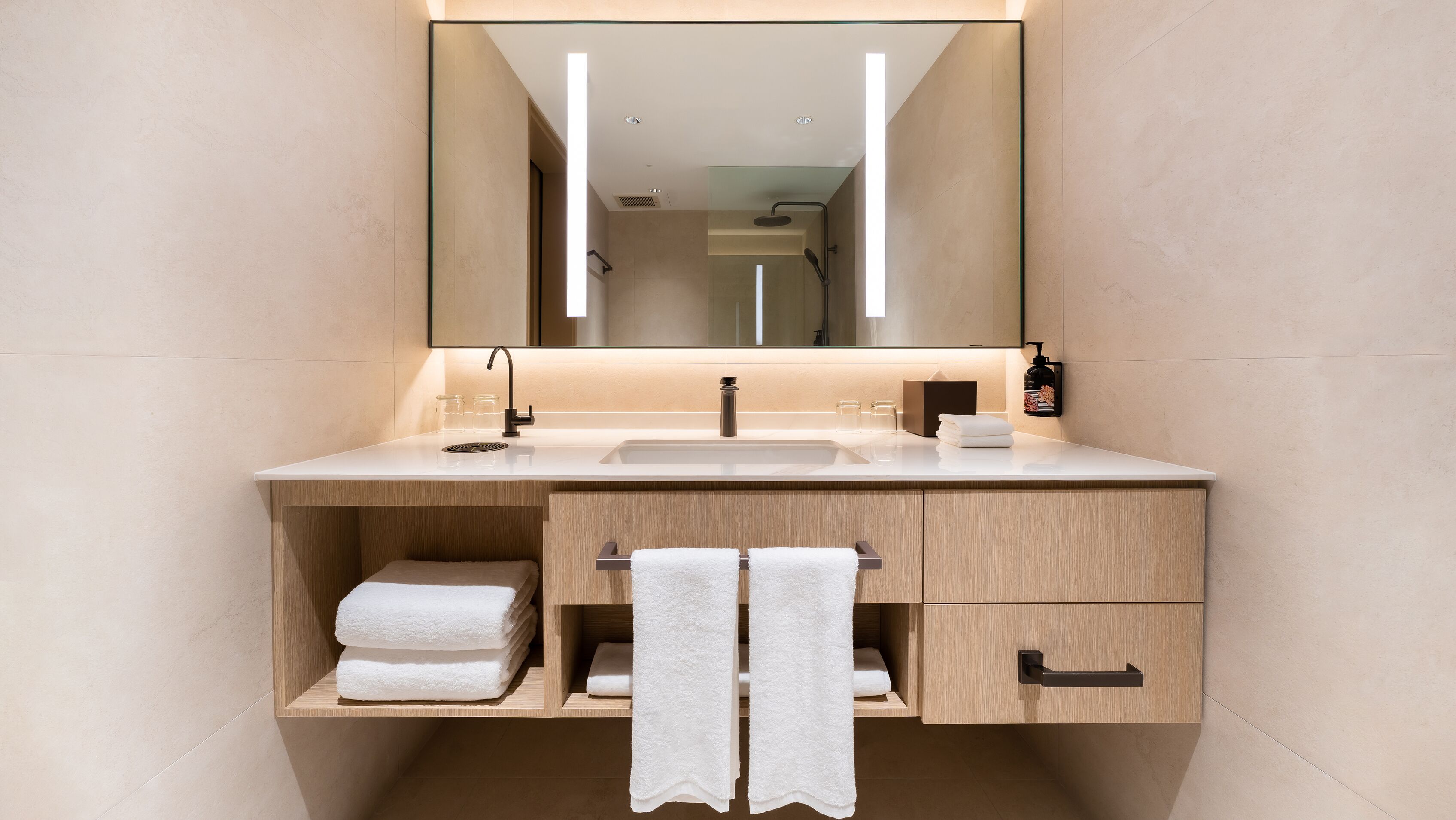 A modern bathroom with a large mirror, a sink, and a towel rack.