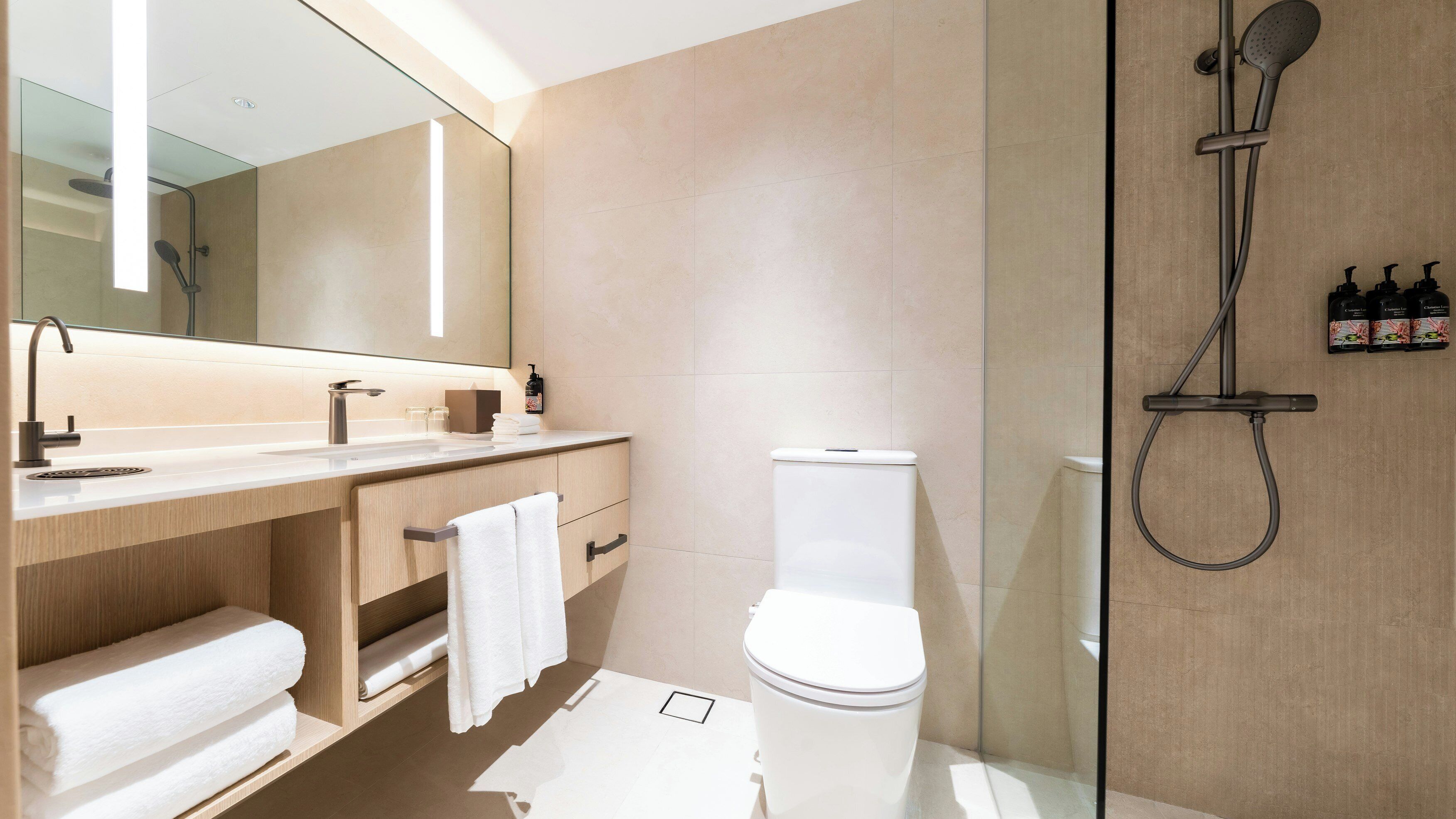 Un baño moderno con cabina de ducha de vidrio, inodoro y tocador con espejo.