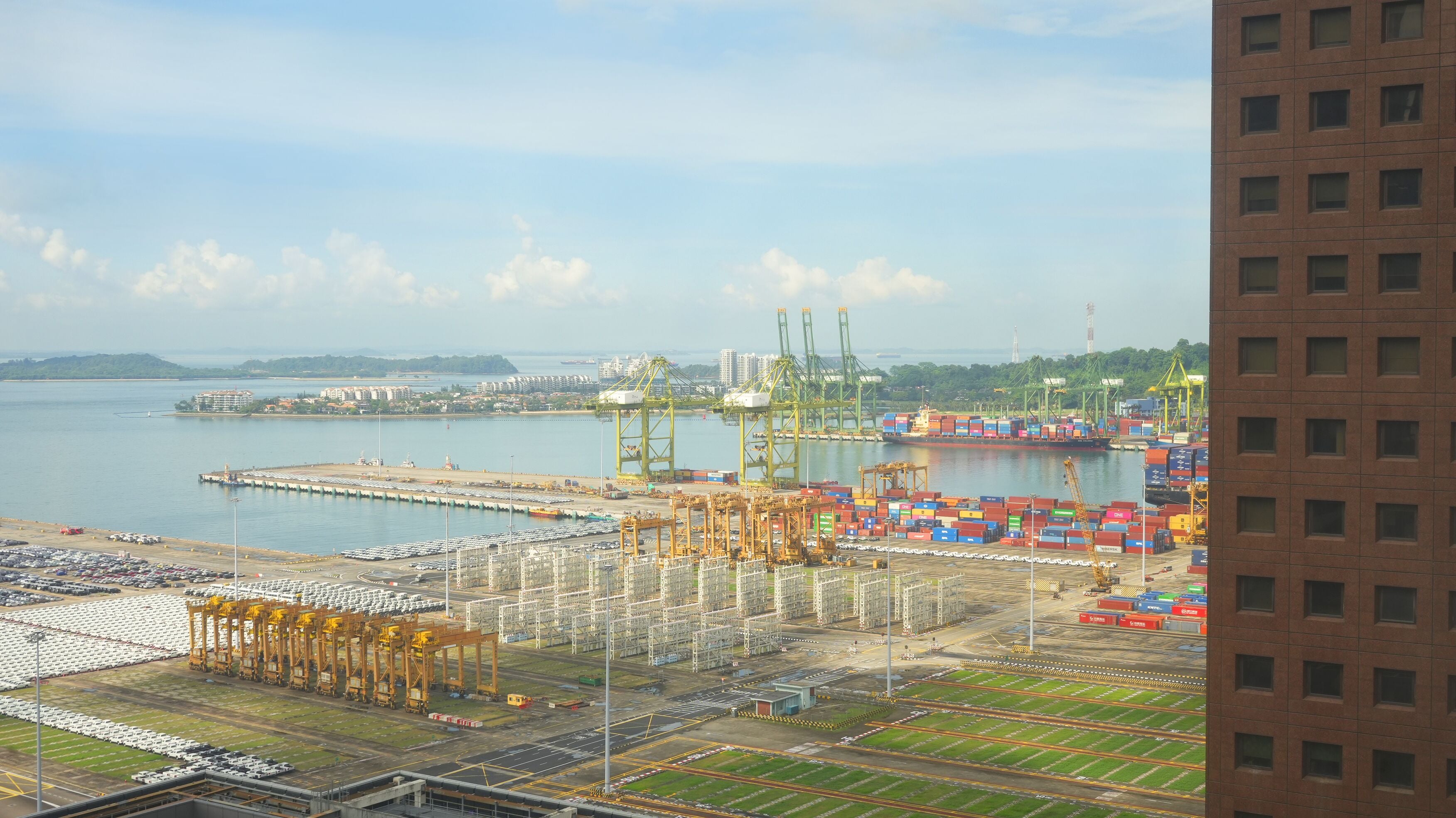 A port with cranes, shipping containers, and a large body of water.