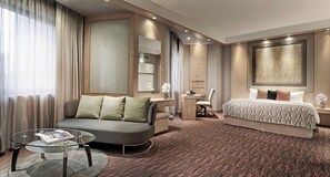 Una habitación de hotel con sofá, cama, escritorio y silla.