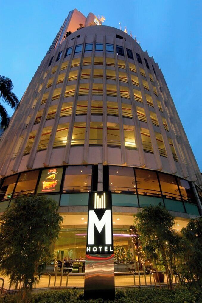 A hotel with a modern design, featuring a prominent 'M' sign and a large glass facade.