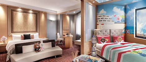 Habitación de hotel con una cama grande, un sofá, un escritorio con juguetes y un mural de un crucero.