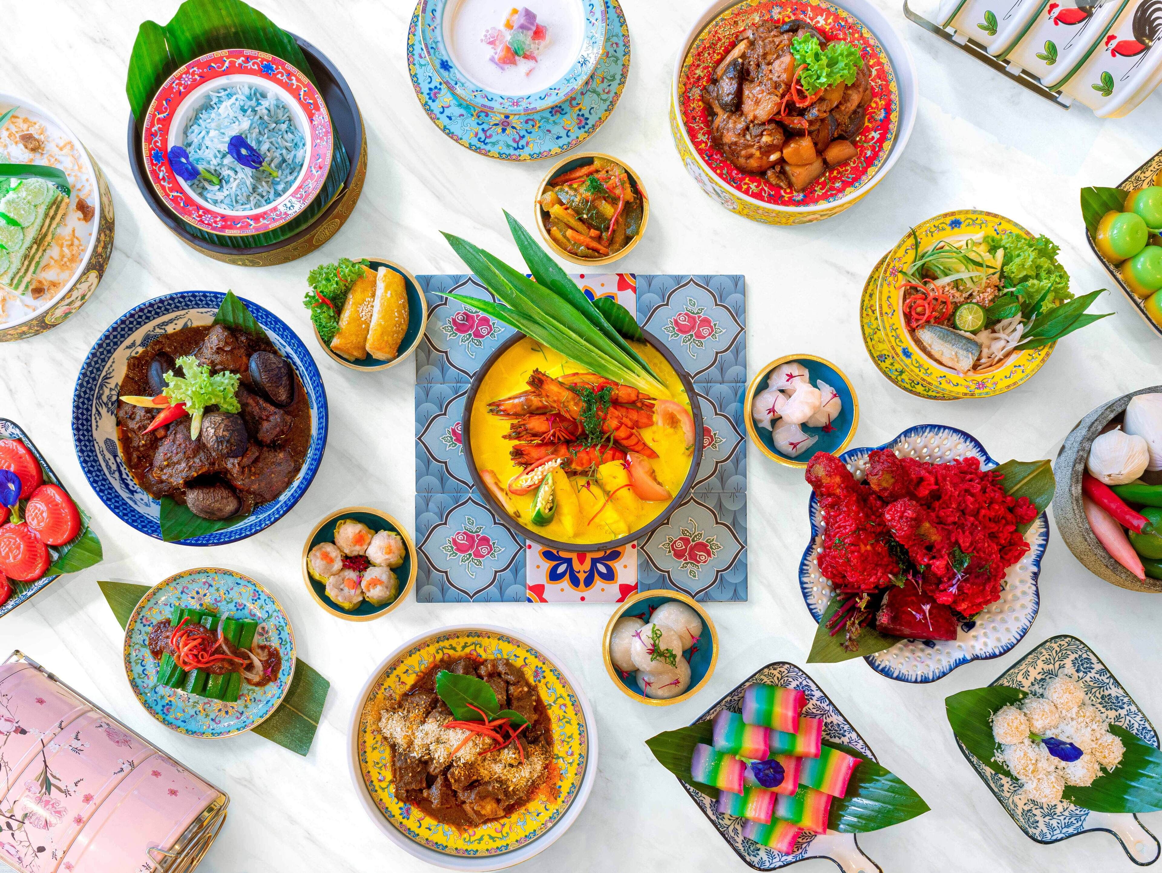 Variedad de platos dispuestos sobre una mesa, incluyendo un plato central con salsa amarilla y mariscos, rodeado de platos más pequeños con diferentes alimentos.