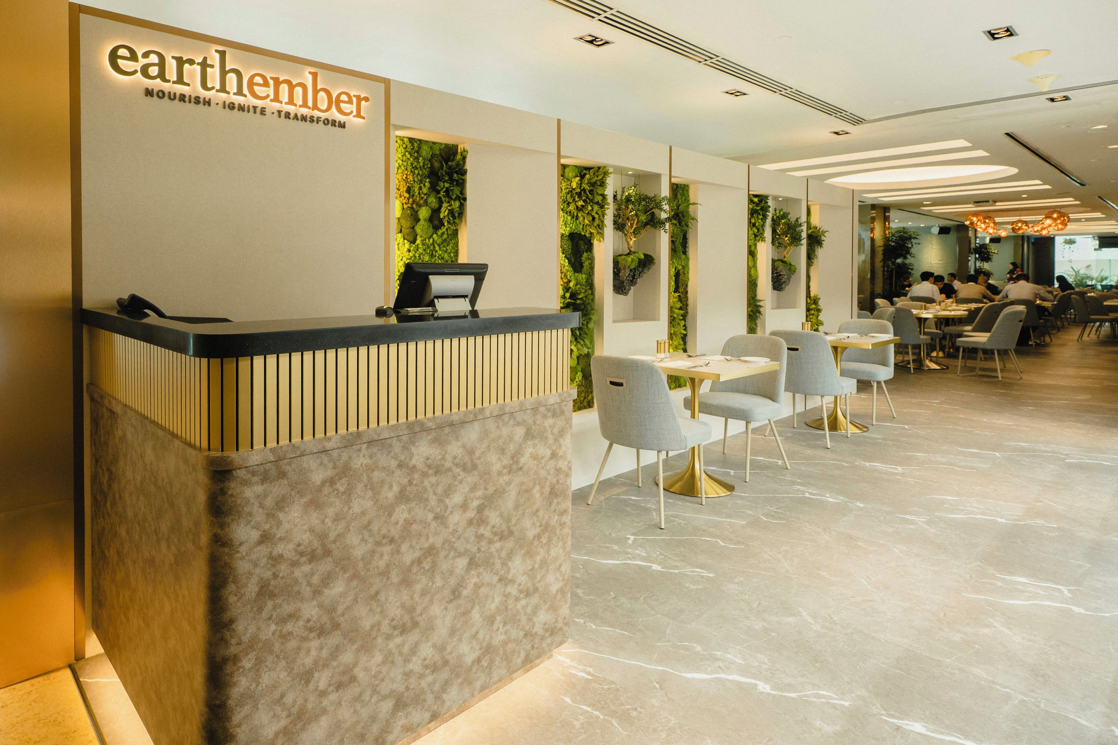 A reception area with a modern design, featuring a reception desk, seating area, and a view into the dining section.