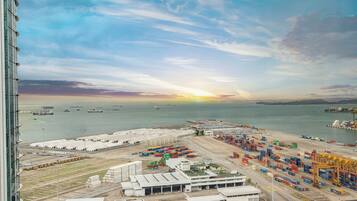 A port area with shipping containers, cranes, and a sunset over the water.