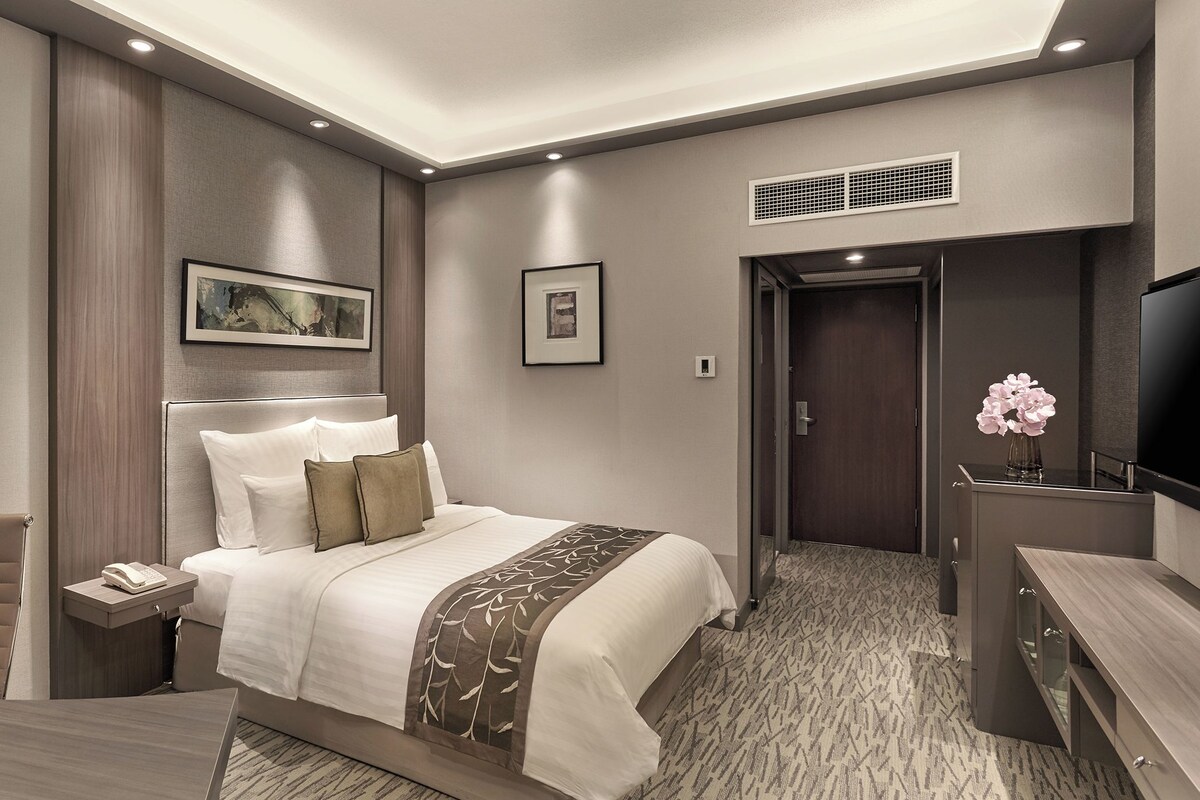 Una habitación de hotel moderna con cama, mesita de noche, silla y televisión.