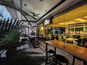 A café with a modern interior, including a ceiling fan, tables, chairs, and a view of the outside. - M Hotel Singapore City Centre (Singapore)