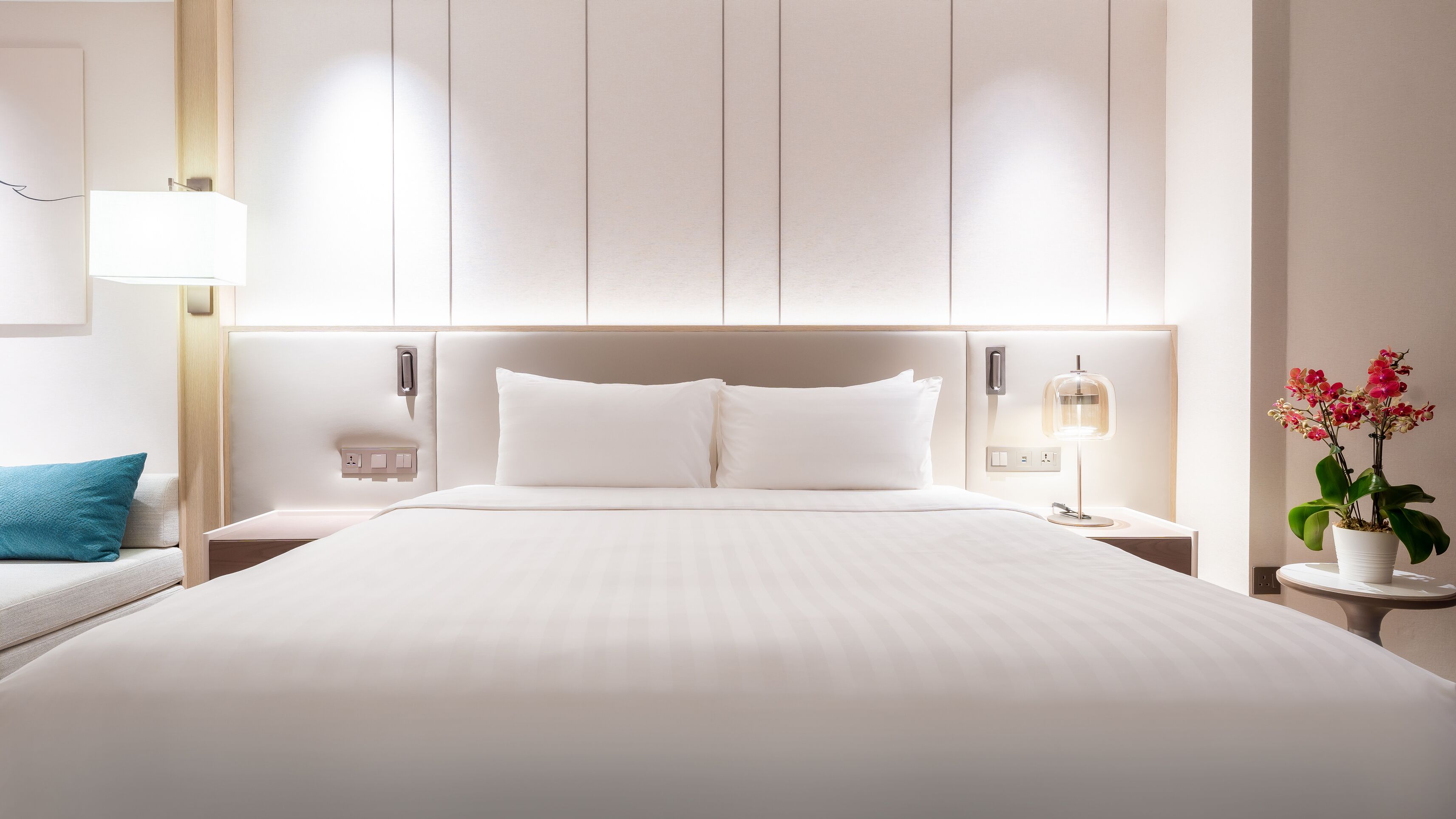 Ein Hotelzimmer mit einem großen Bett, Nachttischen, einer Lampe und einer Zimmerpflanze.