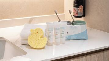 Una encimera de baño con una toalla, una esponja y productos de cuidado de la piel Gentle Goodness.