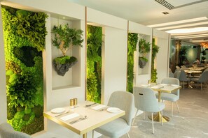 A modern restaurant interior with green wall decorations, tables, and chairs. - M Hotel Singapore City Centre (Singapore)