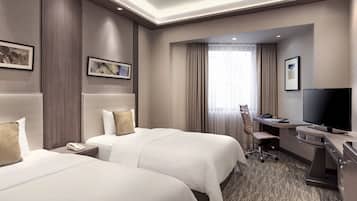 Una habitación de hotel con dos camas, un escritorio, un televisor, un teléfono y una silla.
