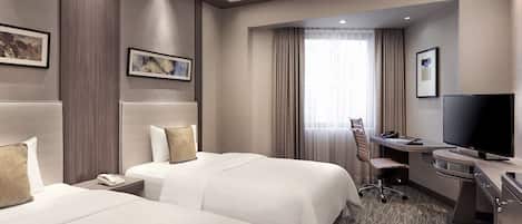 Una habitación de hotel con dos camas, un escritorio, un televisor, un teléfono y una silla.