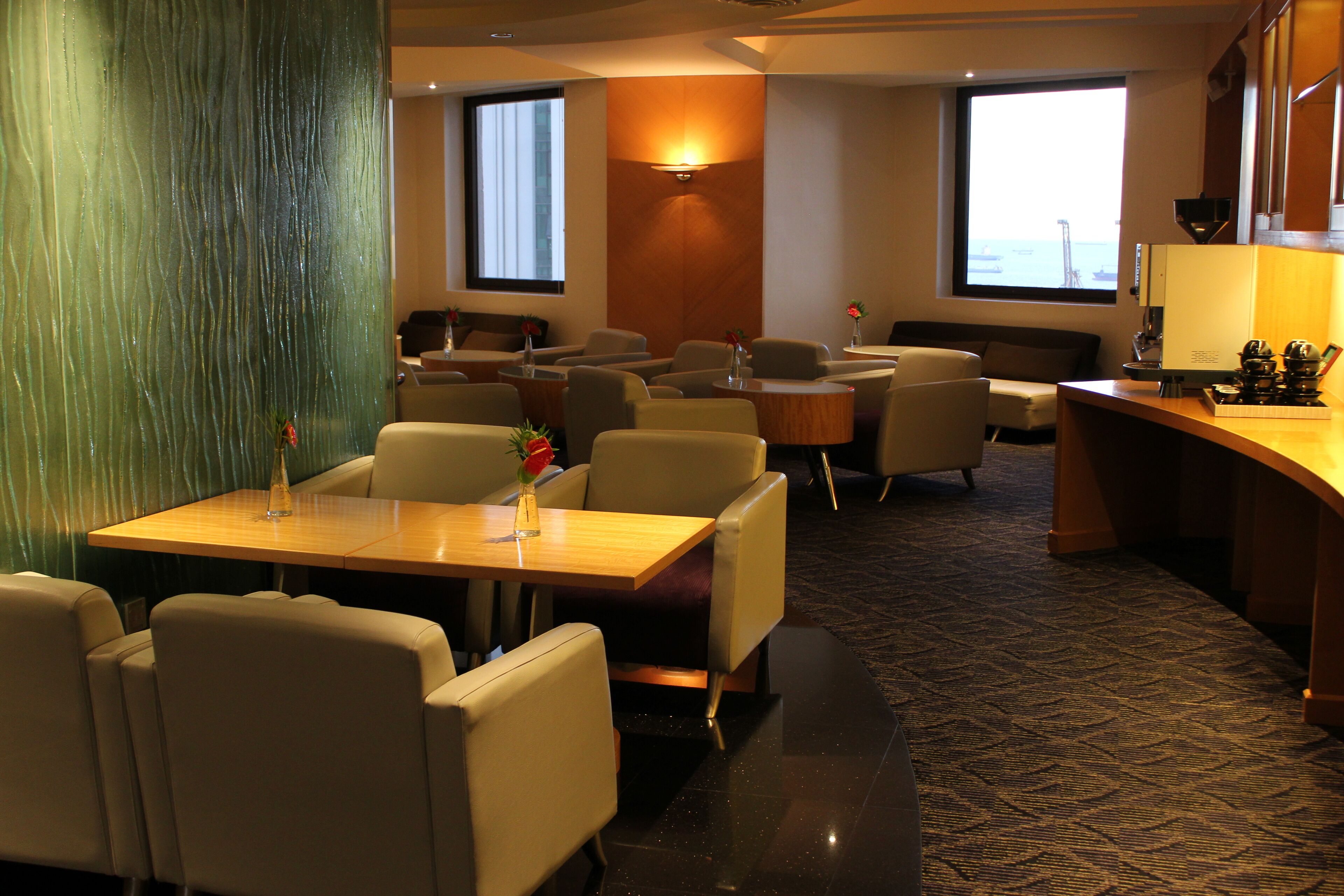 Um saguão de hotel com várias áreas de estar, incluindo um bar e um balcão de recepção.